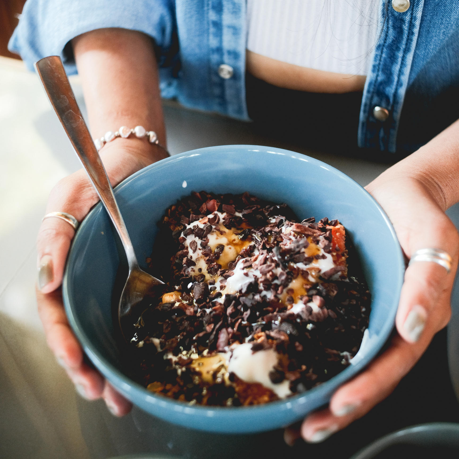 Cacao nibs served in a bowl with fresh fruit and petals ideal for rituals and snacks, 100% dark chocolate, cacoa