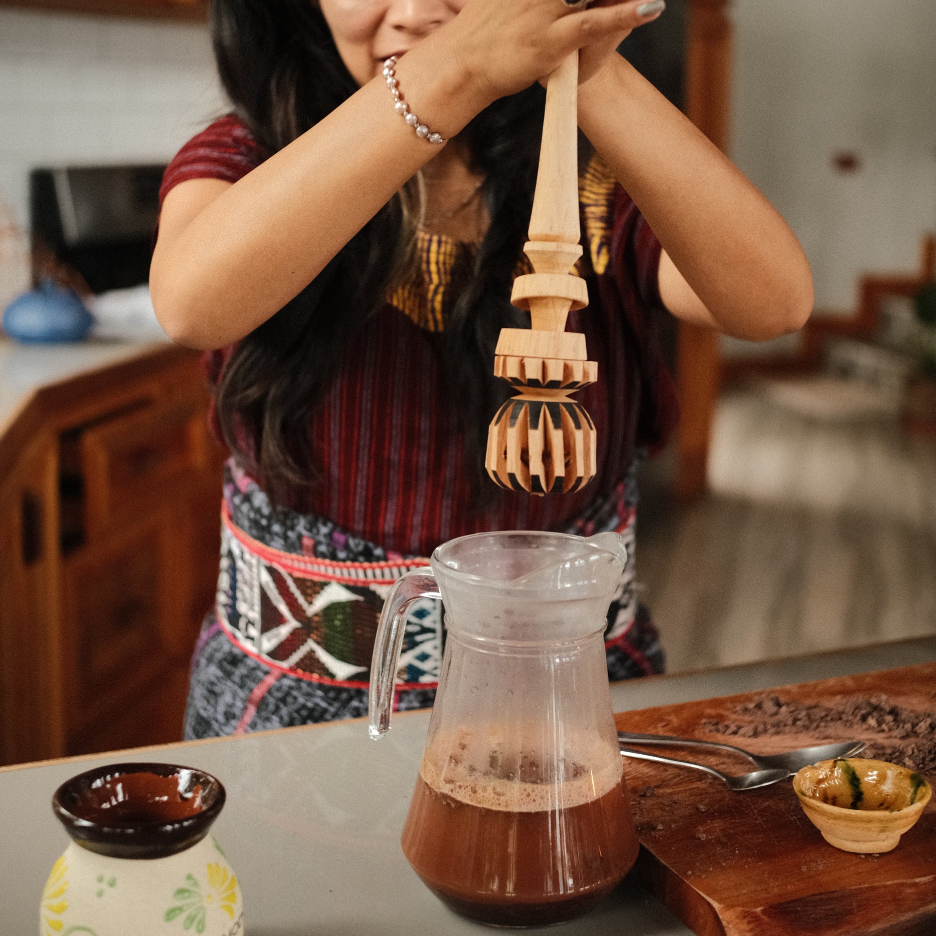 Woman using traditional wooden molinillo to stir ceremonial caca, chocolate molinillo, cocoa mixer