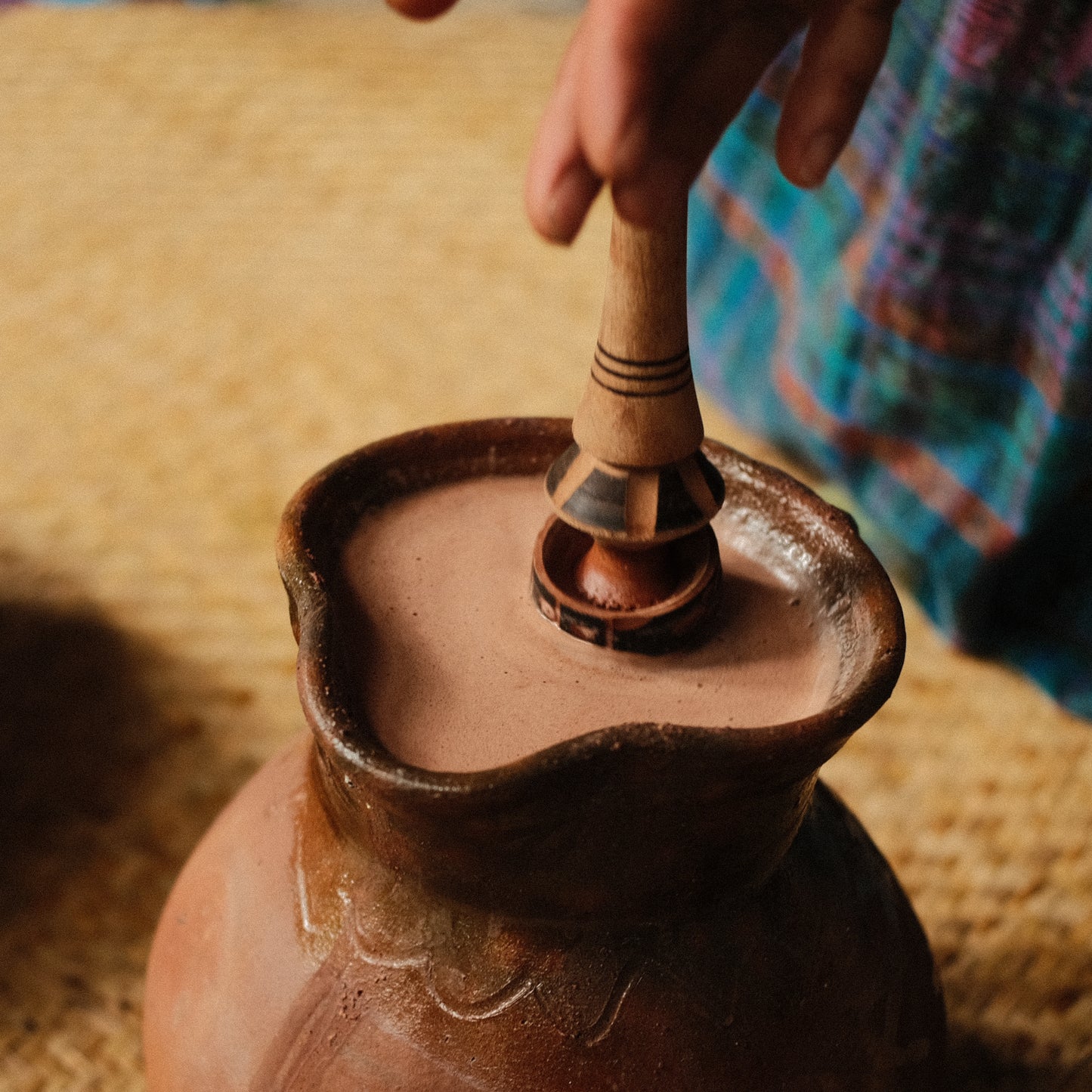 Hand holding cacao nibs above traditional molinillo whisk, molinillo de chocolate, cocoa mixer, ceremonila cacao tool 